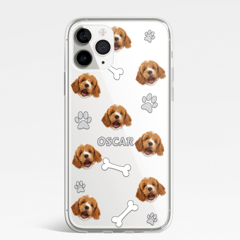 May include: Clear phone case with a repeating pattern of a dog's face, paw prints, and bones. The dog's name "OSCAR" is printed in gray letters on the case.
