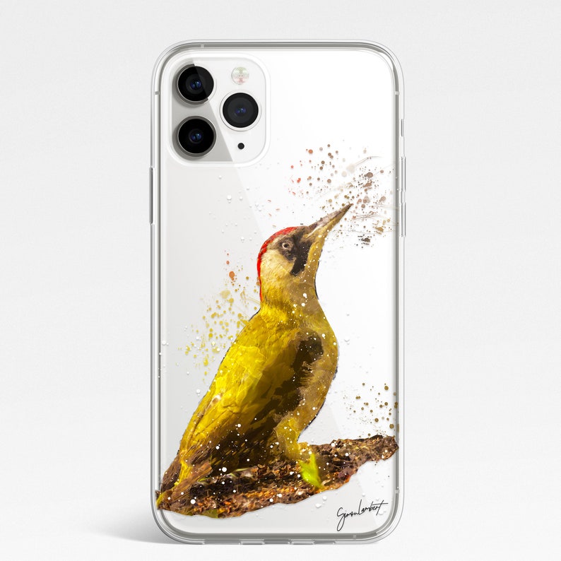 May include: Clear phone case featuring a watercolor painting of a green woodpecker with a red head and black accents. The bird is perched on a brown branch, with paint splatter effects. The artist's signature is visible at the bottom right.