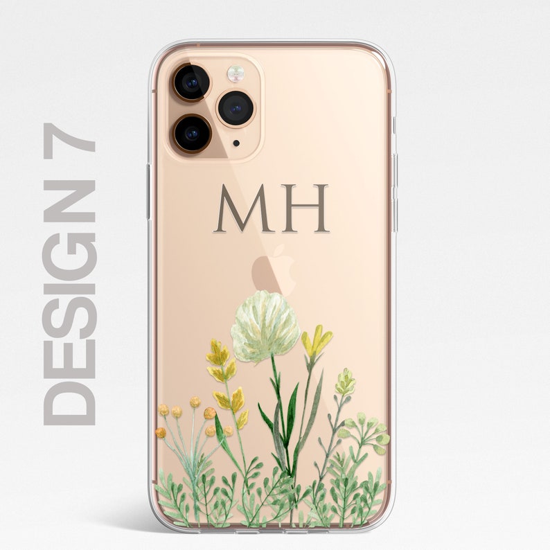 Op de afbeelding: Een transparante telefoonhoes met een gouden achtergrond en een bloemenontwerp. De hoes heeft een monogram met de initialen "MH" in het midden.