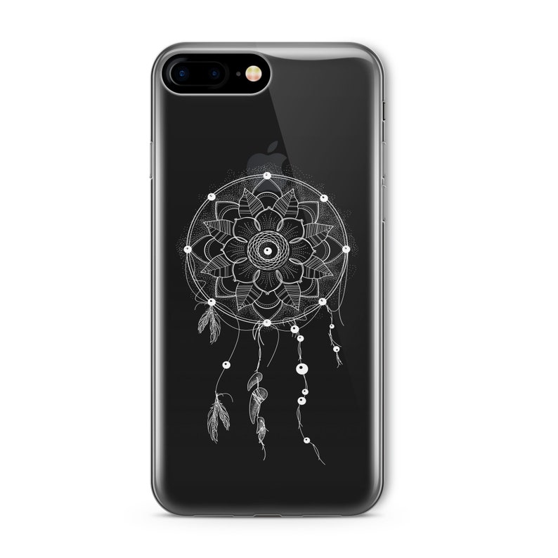 Op de afbeelding: Een transparante telefoonhoes met een zwarte achtergrond en een wit droomvangerontwerp. De droomvanger heeft een cirkelvormig mandala-patroon met veren en kralen die eraan hangen.