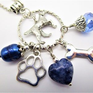 May include: Silver charm necklace with a dog silhouette, paw print, heart, bone, and blue beads.