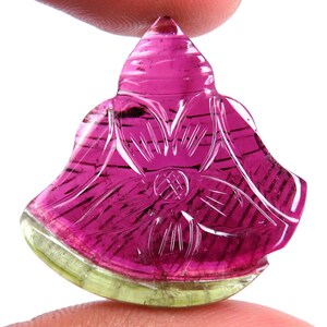 May include: A carved gemstone in a flower shape, featuring a vibrant color gradient. The top is a deep pink, transitioning to a lighter pink and then to a green base. Intricate lines and a floral design are carved into the stone.