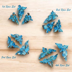 Può includere: Quattro set di ornamenti a forma di foglia turchese, ciascuno con tre pezzi. Le foglie presentano un design dettagliato e venato con accenti marroni. Il testo "1st 3pcs Set", "2nd 3pcs Set", "3rd 3pcs Set" e "4th 3pcs Set" è visibile.