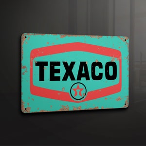 Puede incluir: Un letrero de metal de estilo vintage con fondo turquesa y borde rojo. El letrero presenta la palabra "TEXACO" en letras negras y una estrella roja con contorno blanco.