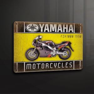 Puede incluir: Una placa de metal de estilo vintage con una motocicleta Yamaha FZR1000 negra y roja de 1990. La placa tiene un fondo amarillo con el logotipo de Yamaha y el texto "Yamaha Motorcycles".