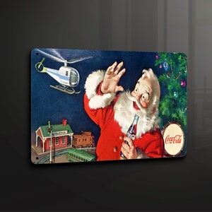 Puede incluir: Un anuncio navideño vintage de Coca-Cola con Papá Noel con un traje rojo y barba blanca, sosteniendo una botella de Coca-Cola. Está de pie frente a un árbol de Navidad y un tren de juguete. Un helicóptero vuela por encima. El texto "Coca-Cola" es visible en un tambor rojo y blanco.