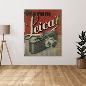 Op de afbeelding: Een vintage advertentie voor Leica-camera's met een rode en witte achtergrond met de tekst "Warum Leica?" en een zwarte en zilveren Leica-camera.