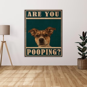 Puede incluir: Un póster de estilo vintage con un perro marrón y blanco mirando directamente al espectador. El póster tiene un fondo azul verdoso y el texto "ARE YOU POOPING?" en blanco.
