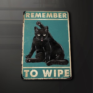 Puede incluir: Un letrero de metal de estilo vintage con un gato negro sentado sobre un fondo azul verdoso. El letrero dice "Remember to Wipe".