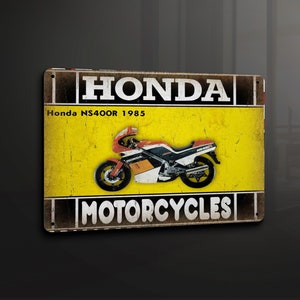 Puede incluir: Un letrero de metal de estilo vintage con fondo amarillo y letras negras. El letrero dice "HONDA MOTORCYCLES" y presenta una motocicleta Honda NS400R negra y roja de 1985.