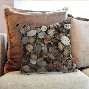 Puede incluir: Una almohada de tiro con un patrón de relojes de bolsillo y esferas de reloj vintage. La almohada está hecha de una tela suave y marrón y tiene una cremallera.