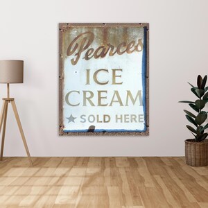 Puede incluir: Un letrero vintage de metal oxidado con pintura blanca que anuncia "Pearces Ice Cream Sold Here".
