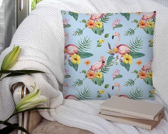 May include: A blue cushion with a tropical print featuring pink flamingos, green leaves and yellow flowers.