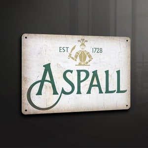 Puede incluir: Un letrero de metal de estilo vintage con un fondo blanco desgastado y texto verde. El letrero presenta una ilustración estilizada de un caballero sosteniendo una espada y el texto "EST 1728 ASPALL".
