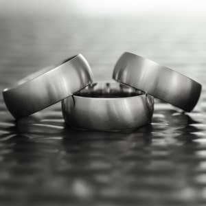 May include: Three silver rings stacked on top of each other. The rings are smooth and have a polished finish.