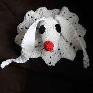 May include: White crocheted amigurumi toy with black eyes and a red nose. The toy is shaped like a dog with floppy ears and a long tail.
