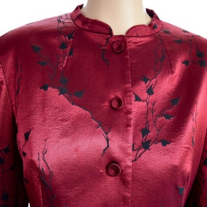 May include: A red satin jacket with a black floral pattern and button closure.