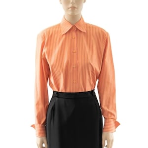 May include: A long-sleeved, orange striped shirt with a button-down collar and a black skirt.