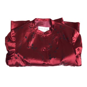 May include: A red satin jacket with a black floral pattern and a white label that reads "Rouge et  Lettres".