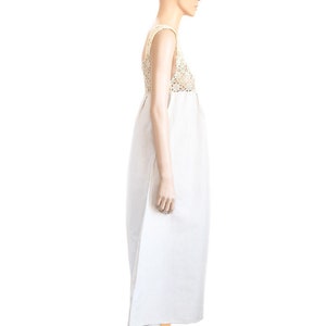 May include: A white maxi dress with a crocheted bodice and a simple, flowing skirt. The dress is worn by a mannequin and has a brown strap sandal on each foot.