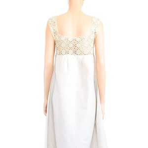 May include: A white maxi dress with a crocheted bodice. The dress has a simple, flowy silhouette and is perfect for a summer day.