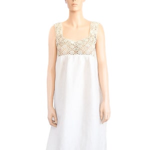 May include: A white linen dress with a crocheted lace bodice. The dress has a sleeveless design and a flowing skirt.