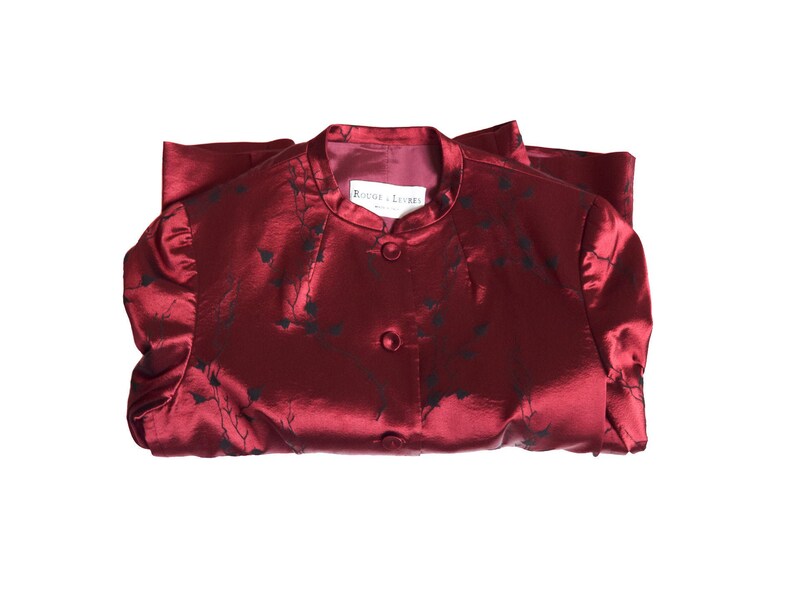 May include: A red satin jacket with a black floral pattern and a white label that reads "Rouge et  Lettres".