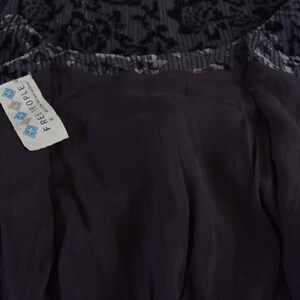 May include: A black velvet dress with a floral pattern and a zipper closure. The dress has a Free People tag attached to the inside.