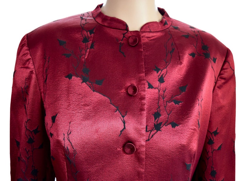 May include: A red satin jacket with a black floral pattern and button closure.