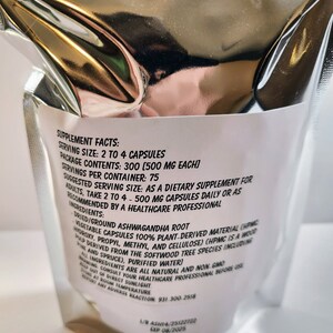 May include: White bag with black text listing supplement facts for Ashwagandha root capsules. Serving size is 2 to 4 capsules, package contains 300 capsules, 500 mg each. Suggested serving size is 2 to 4 capsules daily or as recommended by a healthcare professional. Ingredients include dried/ground Ashwagandha root, vegetable capsules 100% plant-derived material, purified water.