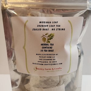 May include: A silver resealable pouch containing 10 tea bags of Moringa Leaf and Soursop Leaf Tea. The label reads "Herbal Tea Contains 10 Tea Bags" and includes the company name "Paisley Farm & Crafts".