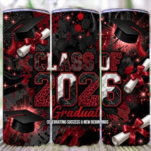 May include: A graduation-themed tumbler with a black, red, and white design. The tumbler features the text "CLASS OF 2026 Graduate" with a mortarboard, diploma, and ribbon accents. The background has a splatter effect.