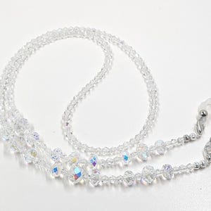 May include: A clear crystal beaded eyeglass chain with silver-toned metal clasps. The chain is made of multiple strands of beads, creating a layered look.