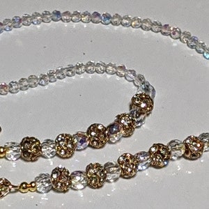 May include: A white beaded chain with gold beads and gold clasps. The chain is approximately 24 inches long.