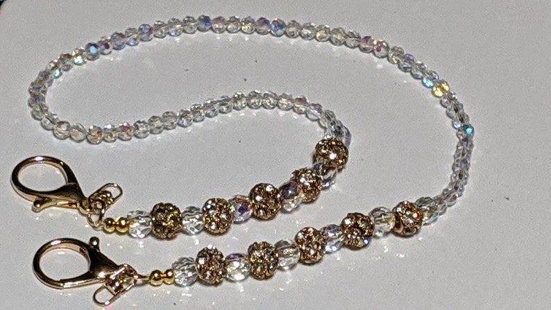 May include: A white beaded chain with gold beads and gold clasps. The chain is approximately 24 inches long.
