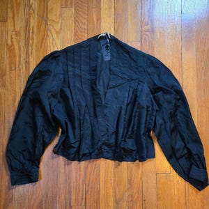 May include: A set of three ceramic mugs with a speckled, matte finish. The mugs are in shades of cream, light gray, and dark gray. Each mug has a simple, minimalist design and a rounded handle.