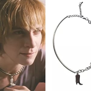 May include: A silver chain necklace with a small boot charm. The boot is brown and has a pointed toe.