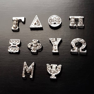 May include: A set of 10 silver Greek letter charms with rhinestones. The letters are: Gamma, Delta, Theta, Pi, Epsilon, Phi, Psi, Omega, M, and Psi.