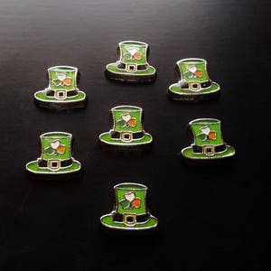 May include: Seven green and silver leprechaun hats with a shamrock design. The hats are on a black background.