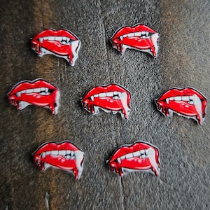 May include: Eight red and white vampire fangs with dripping blood, perfect for Halloween decorations or crafting projects.