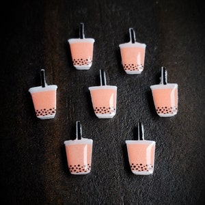 May include: Seven pink and white bubble tea charms with black straws and black boba pearls.