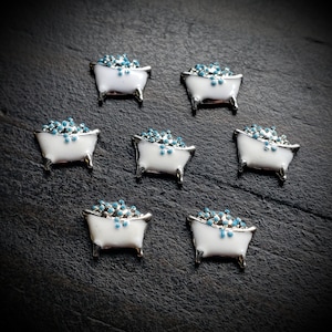 May include: Seven white bathtub charms with blue bath bubbles. The charms are small and have a silver finish.