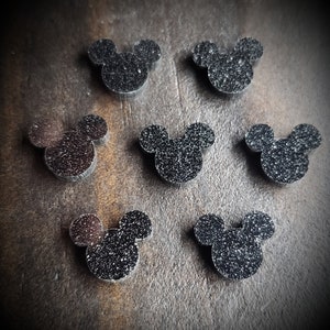 May include: Seven black glitter Mickey Mouse head shapes.