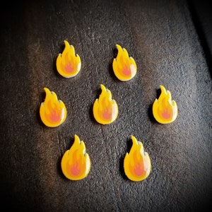 May include: Seven yellow flame-shaped buttons with red centers. The buttons are arranged in a circle on a dark brown surface.