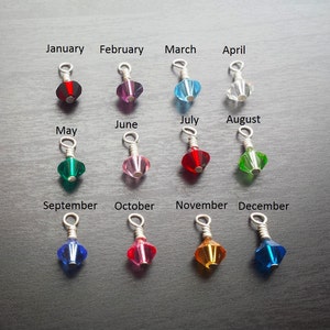May include: Twelve crystal charms, each representing a month of the year. The charms are silver-toned and have a small loop at the top. The crystals are in various colors, including red, pink, blue, green, and clear.