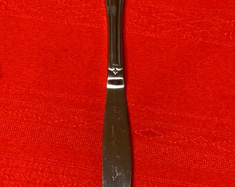 May include: A silver butter knife with a decorative shell design on the handle.