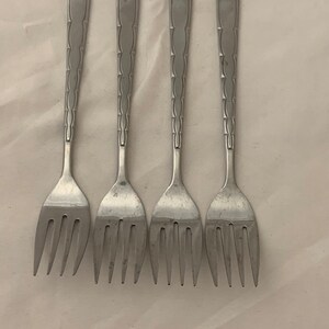 May include: Four silver forks with a decorative pattern on the handle.