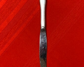 May include: A silver dinner knife with a white handle and a slightly curved blade.