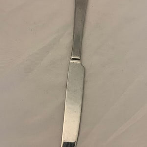 May include: A silver dinner knife with a slightly curved blade and a straight handle.