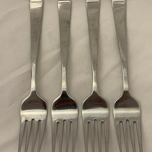 May include: Four silver forks with square-shaped handles.